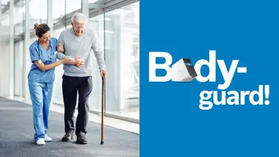 A corridor with a large window front through which the sun is shining. A woman in light-blue work clothes with a stethoscope around her neck has linked arms with an old man with a walking stick and is leading him.